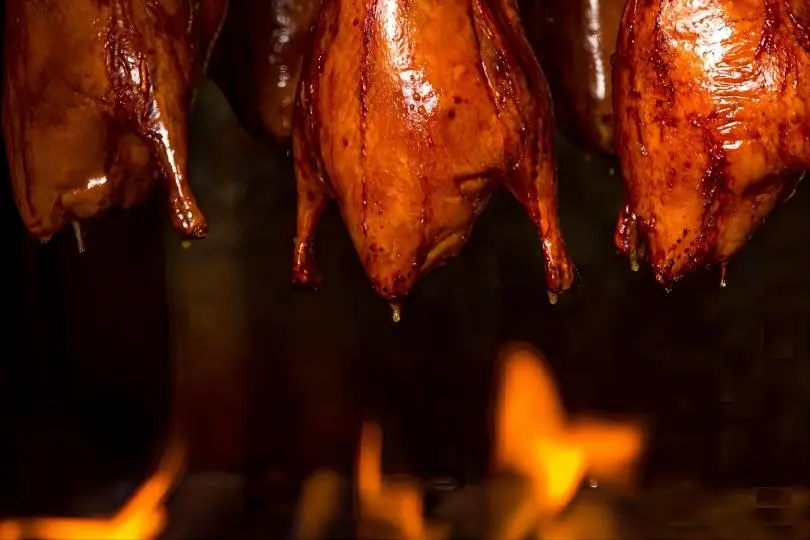 Beijing Roast Duck being roasted over fruitwood charcoal, crispy skin and tender meat on Beijing local food trails