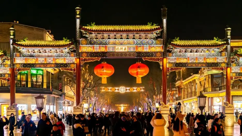 Dashilar Commercial Street entrance at dusk, neon lights glowing and crowds exploring Beijing’s historic food street.