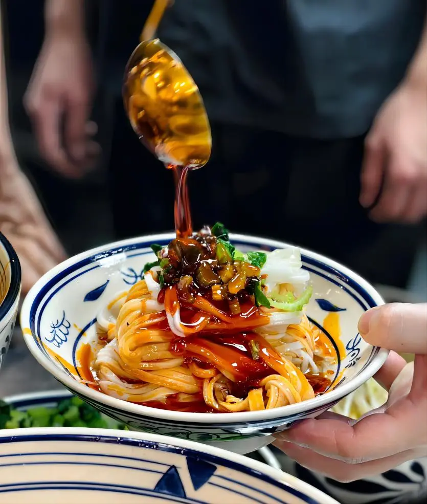Liangpi cold noodles Xi’an street food, vendor adding chili oil