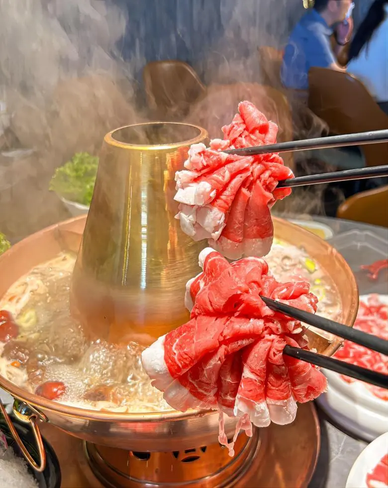 Traditional Old Beijing copper pot hot pot with thinly sliced lamb, clear broth, and dipping sauces