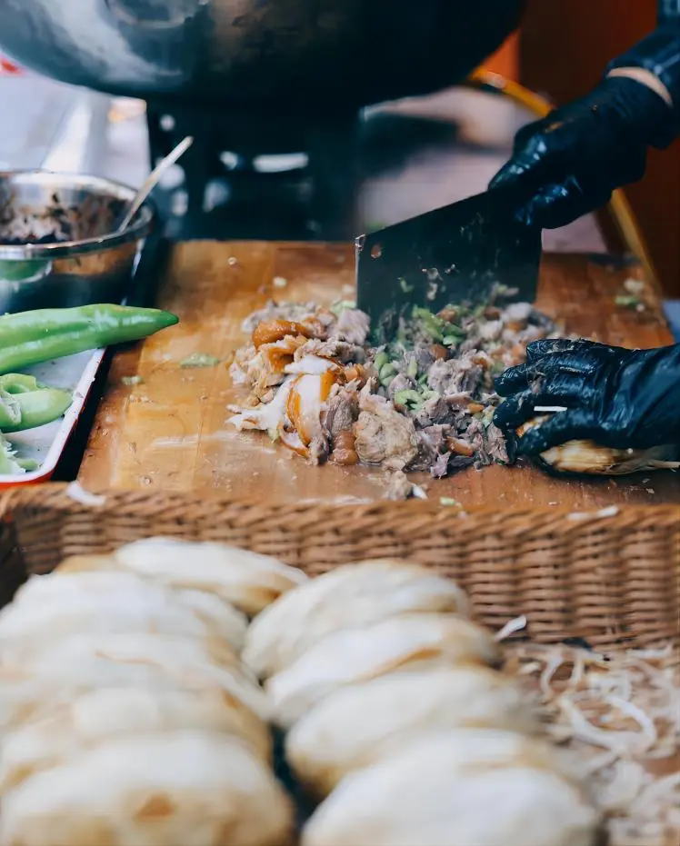 Rou Jia Mo Xi’an Chinese burger being prepared by street vendor, pork being chopped