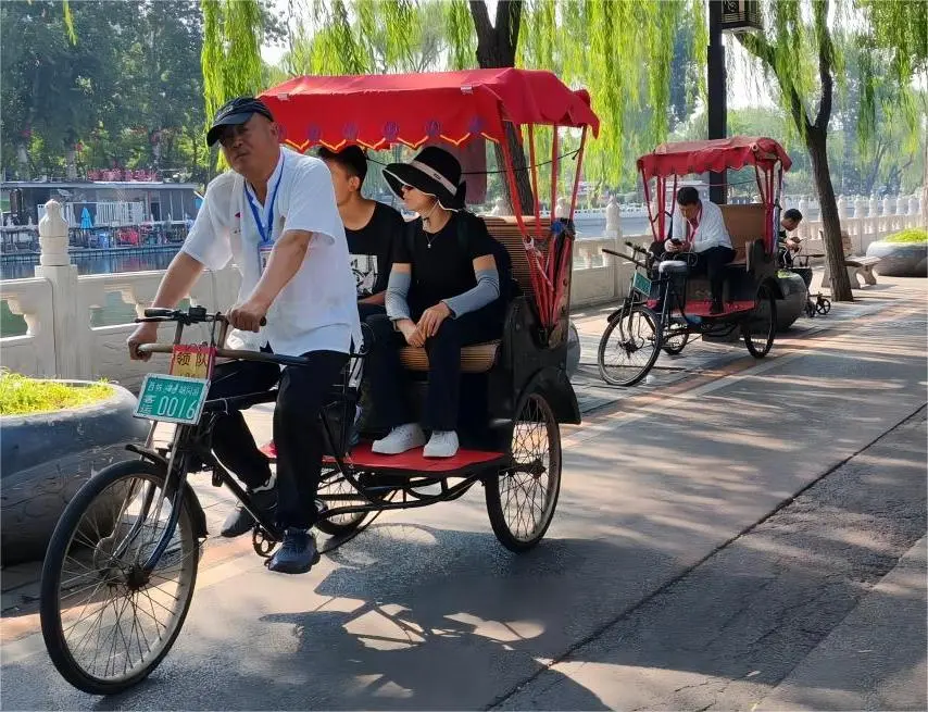 Rickshaw carrying tourists along the lakeside of Shichahai, Beijing, showcasing traditional hutong culture