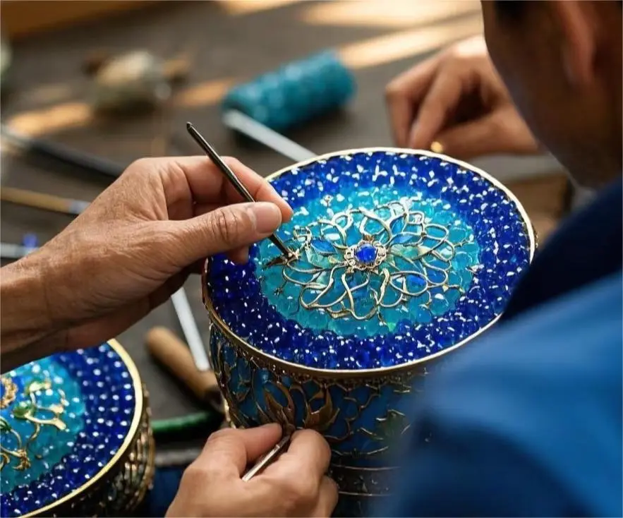Artisan shaping fine copper wires during the filigree inlay process of Cloisonné Beijing, a traditional enamel art technique.