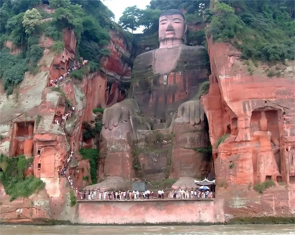 Tourists standing at the feet of the Leshan Giant Buddha, showing the immense scale of the world’s largest stone-carved statue.