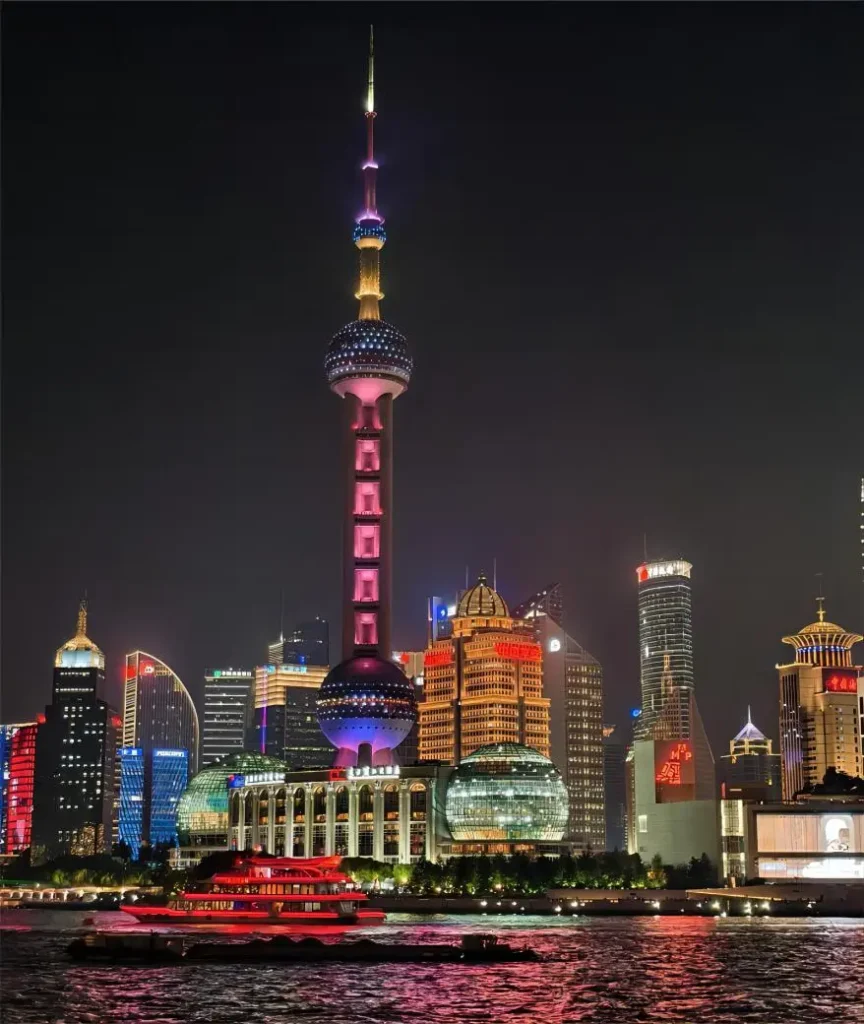 Night view of the Oriental Pearl Tower illuminated with colorful lights against the Shanghai skyline