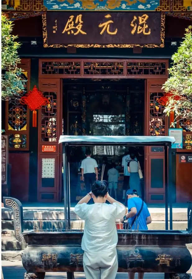 Visitors praying amid incense smoke at Qingyang Palace Chengdu, experiencing Taoist culture and blessings