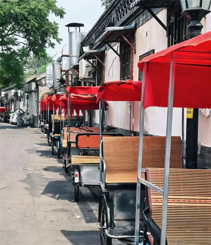 Traditional tricycle rickshaw parked in a Beijing hutong alley, reflecting local life and classic street culture.