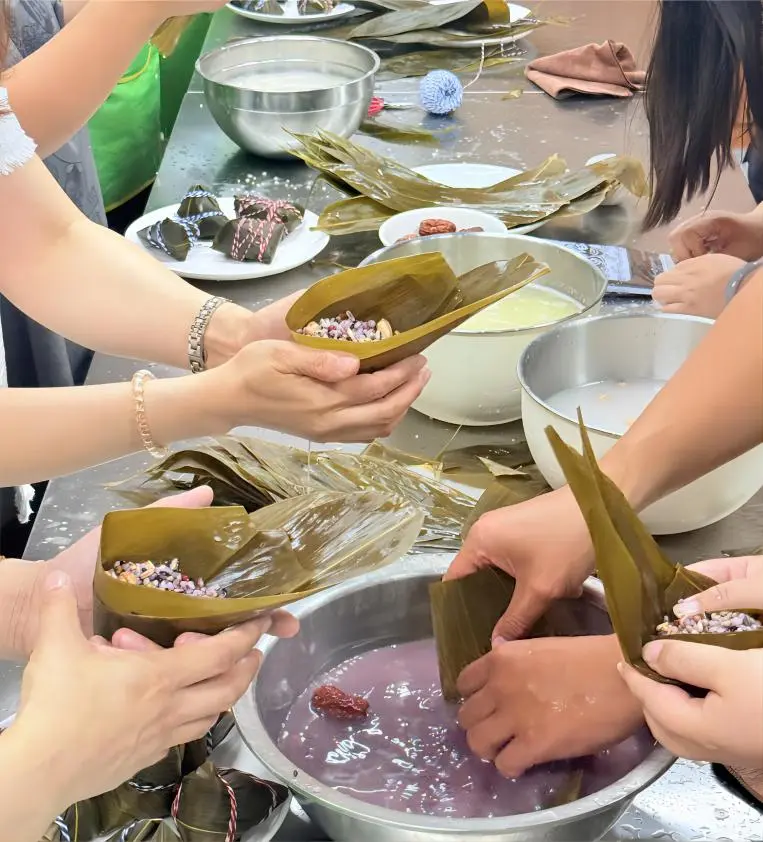People wrapping zongzi together for the Dragon Boat Festival, showing traditional Chinese holiday food culture.