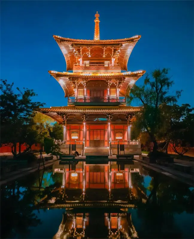 Night view of Fulin Pagoda at Guangfulin Shanghai with warm lights reflecting on the lake.