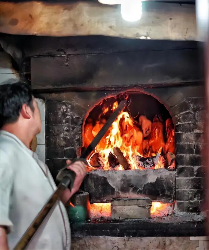 Peking Duck roasting over pear wood fire at Liqun restaurant in Beijing hutong