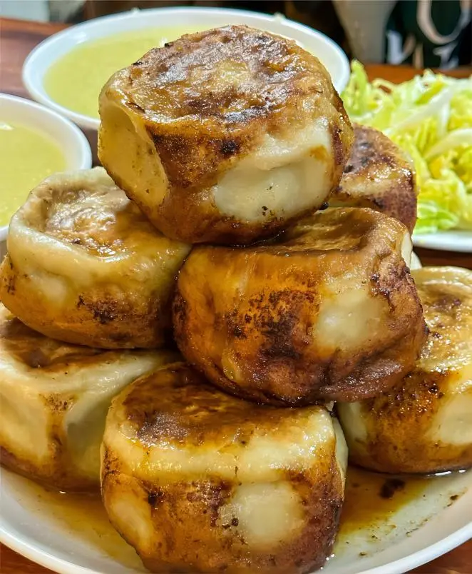 Close-up of golden crispy Mending Roubing with juicy meat filling, traditional Old Beijing snack