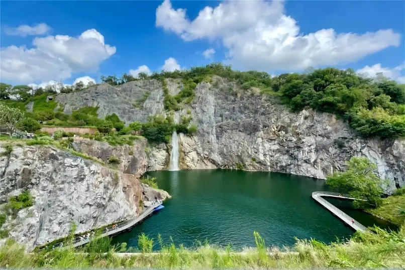 Quarry Garden scenic view at Shanghai Chenshan Botanical Garden, showcasing cliffs, lake and lush greenery.