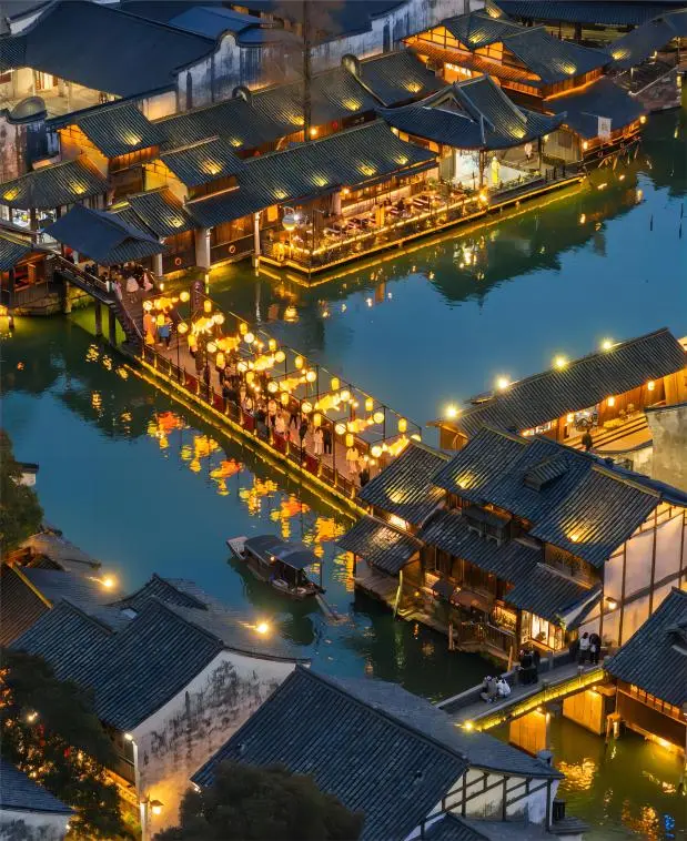Aerial night view of lantern-lit Wuzhen, revealing its glowing canals and rooftops for day trip travelers from Shanghai.