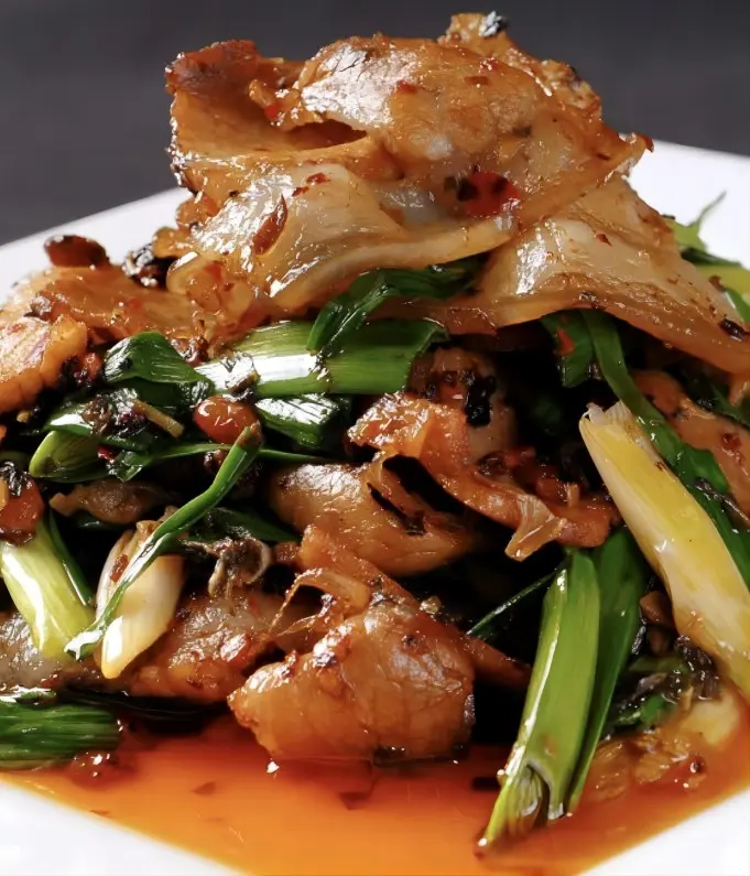 Close-up of authentic Chengdu Twice-Cooked Pork (Hui Guo Rou) with garlic sprouts
