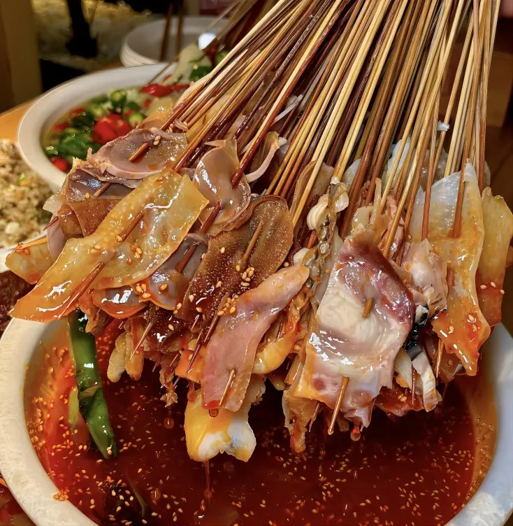 Close-up of meat Bo Bo Ji skewers in rich red chili oil, classic Sichuan street food