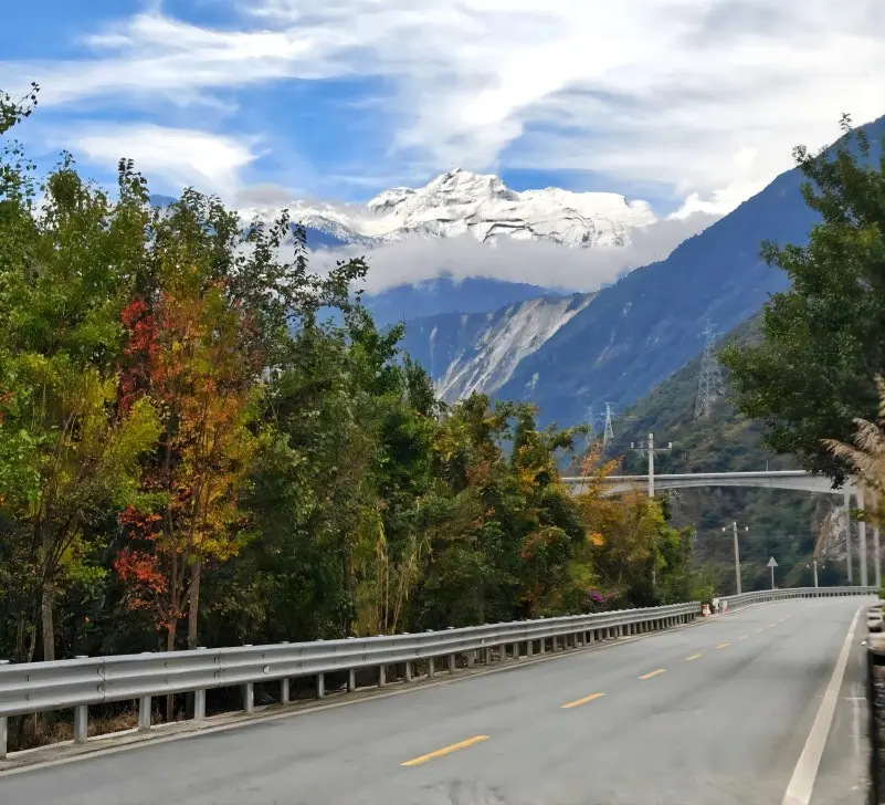 Mountain road leading to Moxi Ancient Town with snow-covered peaks in western Sichuan