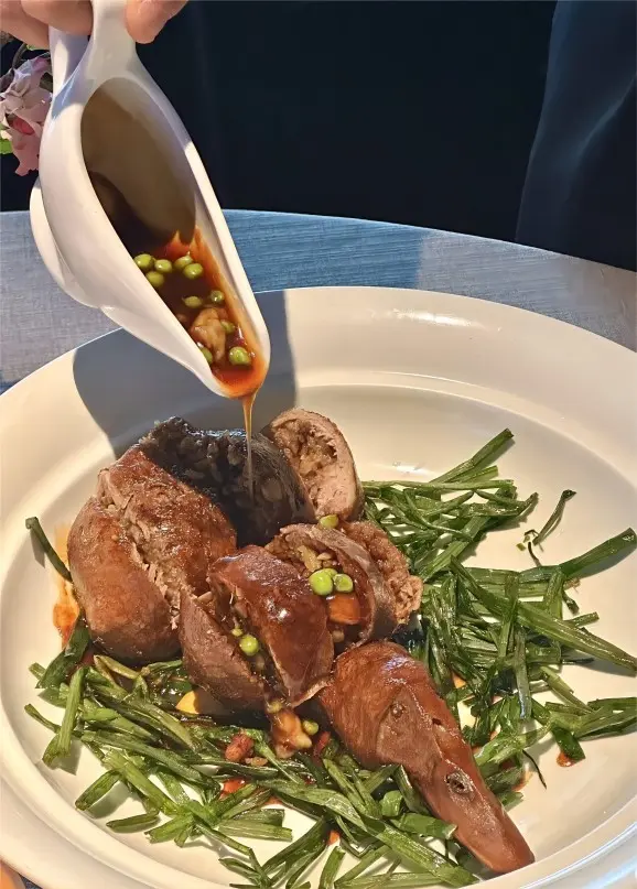 Shanghai Eight-Treasure Duck cut open with sauce poured over the glutinous rice filling, showcasing classic Benbang flavors.