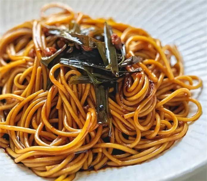Close-up of Shanghai scallion oil noodles showing glossy scallion oil and springy noodles.
