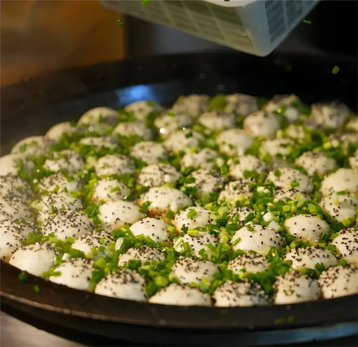 Shanghai Shengjian (Pan-Fried Buns) being cooked in the pan, crispy bottoms forming