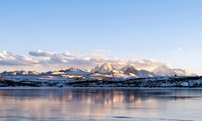 Sunlight and mountain reflections on the calm waters of Si Ding Cuo Sacred Lake