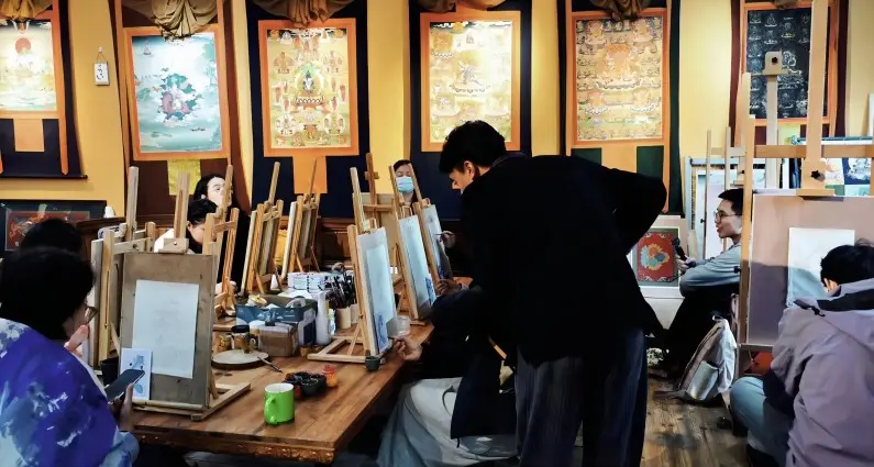 Visitors experiencing a Thangka painting workshop in Moxi Ancient Town, learning traditional Tibetan art