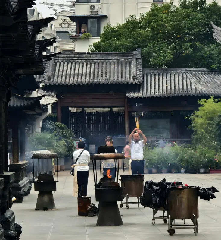 Visitors offering incense and praying at Zhenru Temple in Shanghai, reflecting local Buddhist traditions.