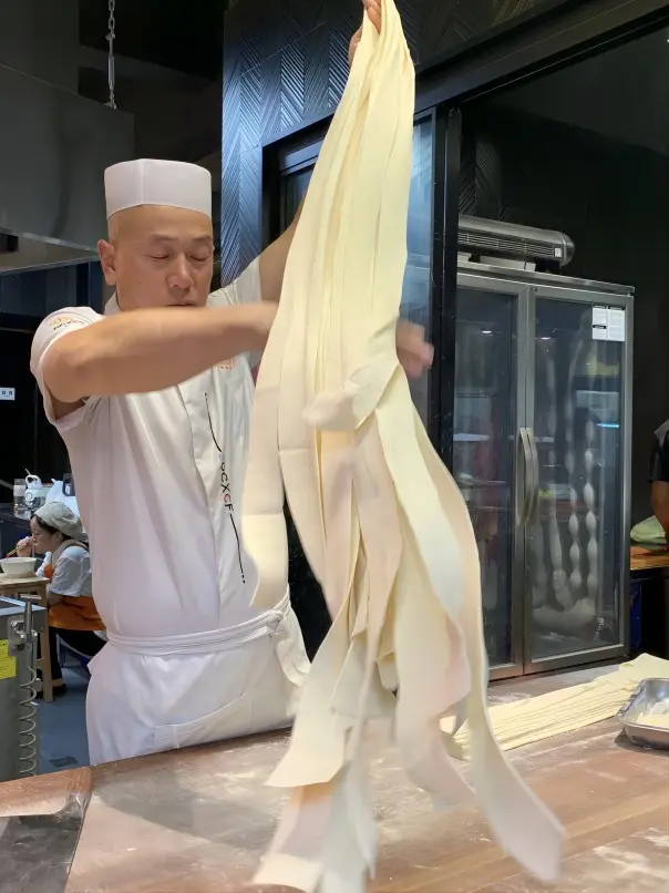 A chef hand-pulling Biangbiang noodles in Xi’an using the traditional belt-wide technique