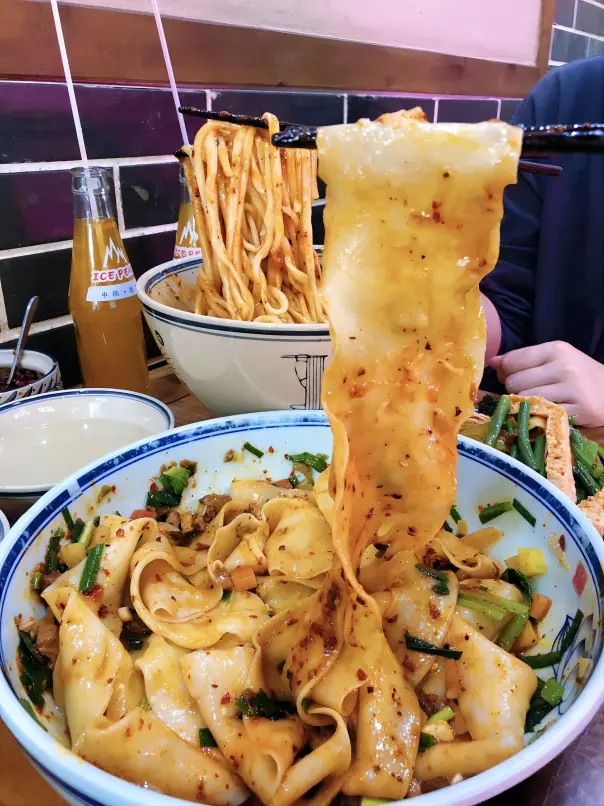 A finished bowl of Xi’an Biangbiang noodles with chili oil and hand-pulled belt-wide noodles