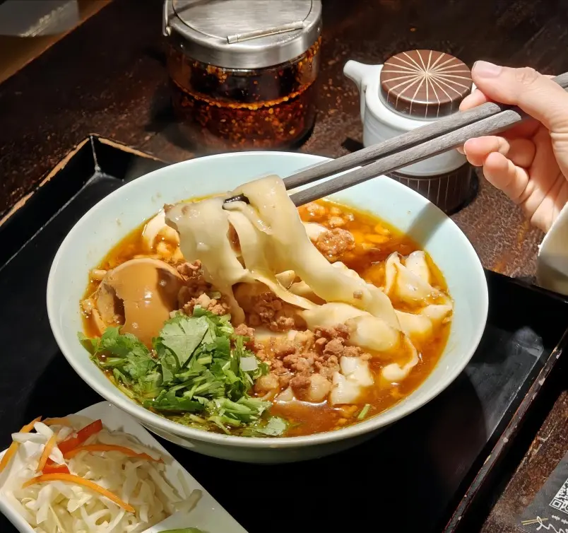 A plate of Datong Daoxiao Mian, thick noodles shaved by hand, topped with savory pork or beef gravy, a local culinary specialty.