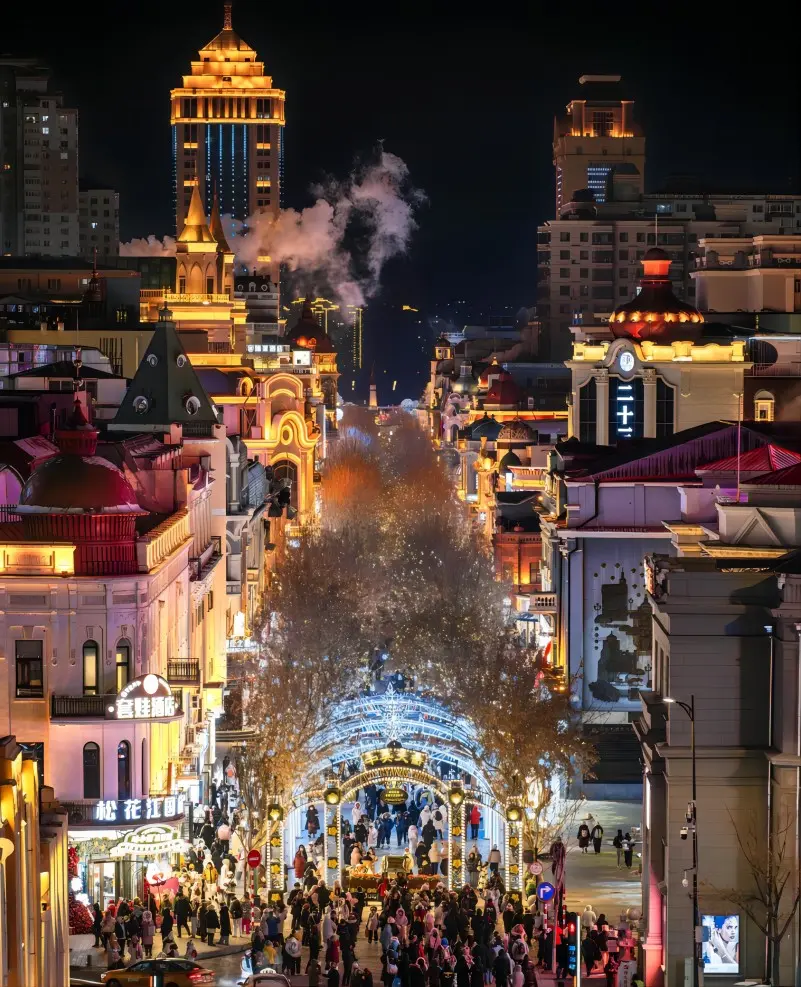 Central Street in Harbin at night with bright lights and snowy cobblestone street