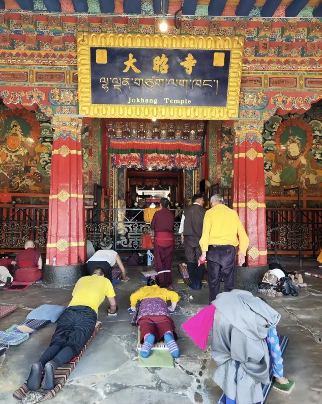 Pilgrims performing full-body prostrations in front of the main hall of Jokhang Temple in Lhasa