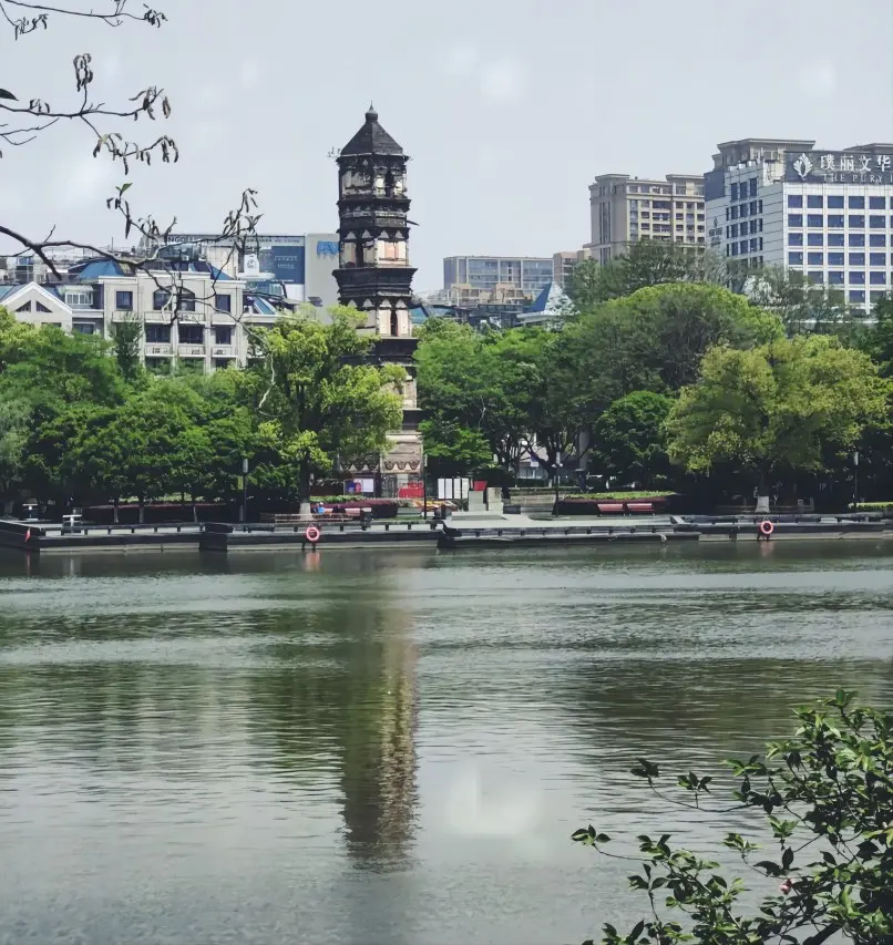 Yiwu Xiu Lake Park with Da'an Temple Tower on a clear day, a peaceful green space for locals and tourists.