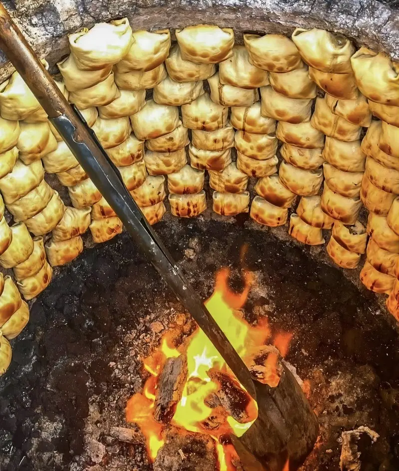 Baked meat buns (Shamusa) cooking in a traditional oven in Yining, Xinjiang