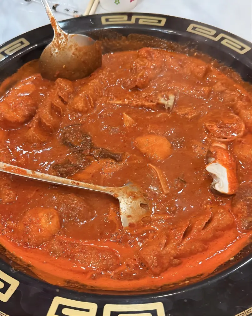 A steaming bowl of spicy hu hu, a Ningxia specialty with a rich, spicy broth served with noodles and vegetables.