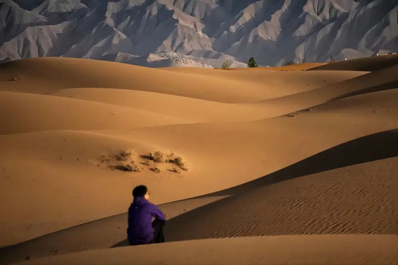 A stunning view of the Tengger Desert at dusk, with the orange glow of the setting sun over the sand dunes.