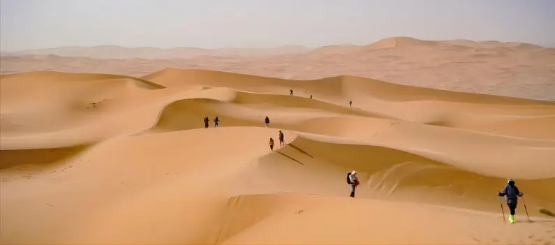 Tourists crossing the vast sands of Tengger Desert, experiencing the desert’s expansive beauty.
