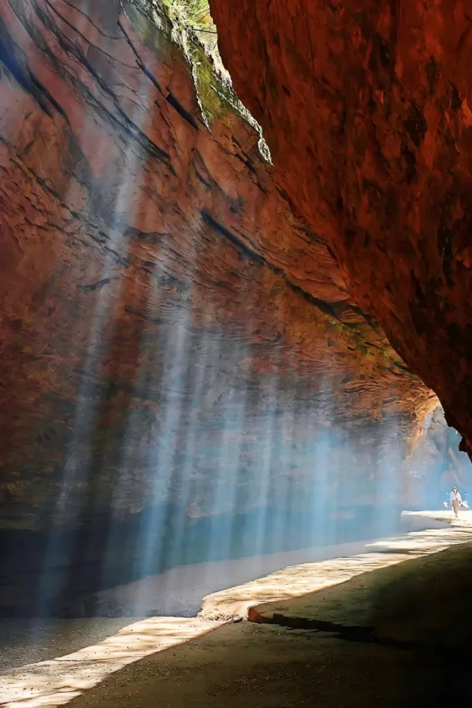 Visitor walking through sunlight beams inside Yucha Grand Canyon