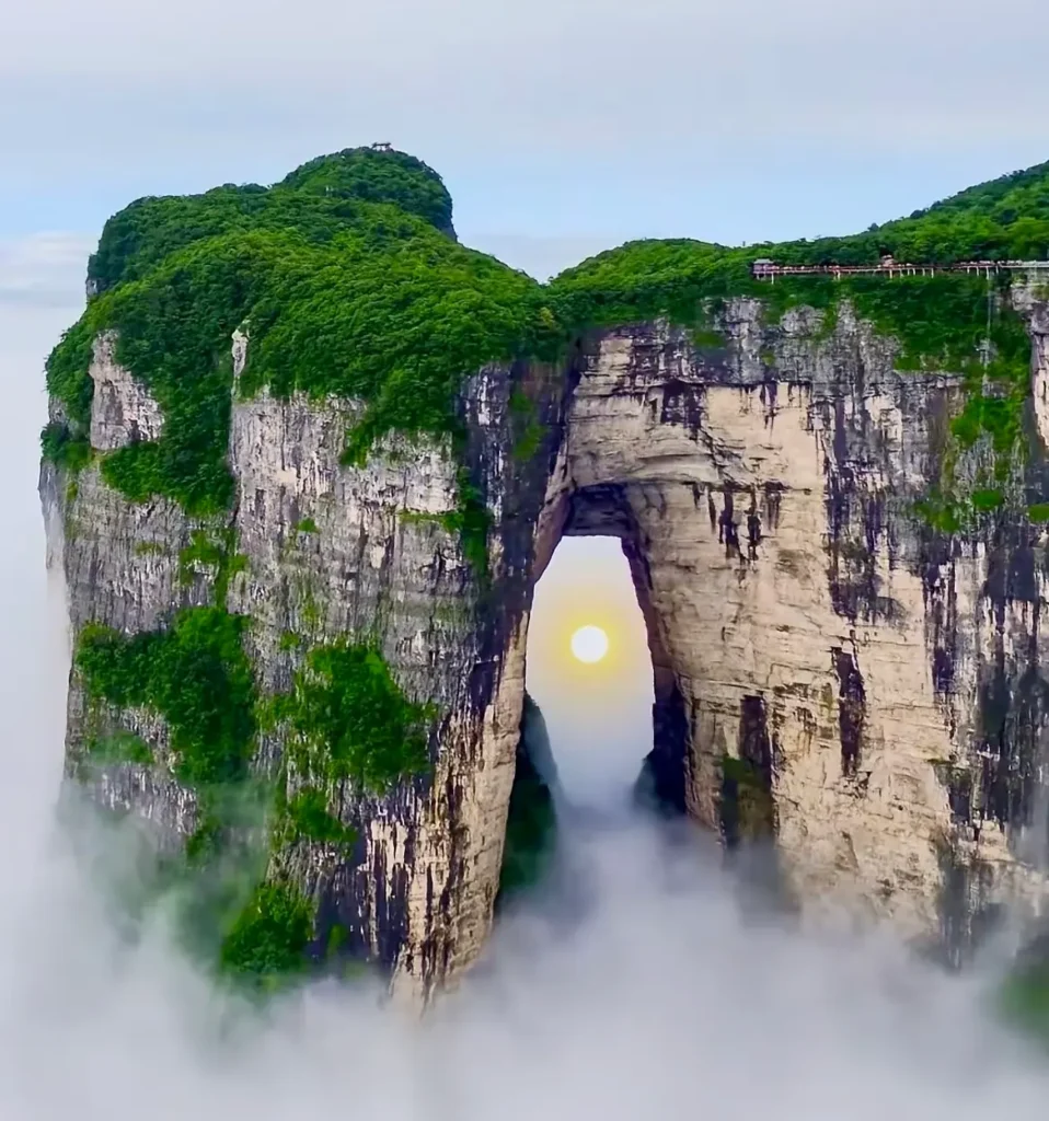 Golden morning sunlight glowing through the natural arch of Tianmen Cave at Tianmen Mountain, one of the most famous Zhangjiajie tourist attractions.