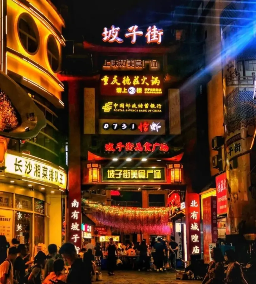 Pozi Street in Changsha bustling with visitors and illuminated restaurant signs at night.
