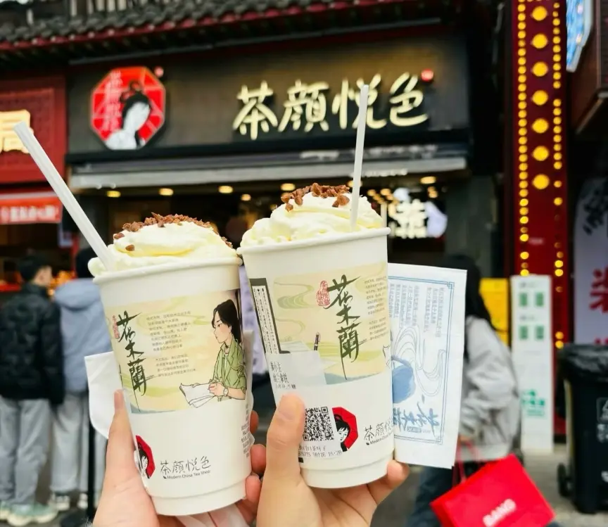 A visitor holding a cup of Chayan Yuese milk tea outside a tea shop in Changsha.