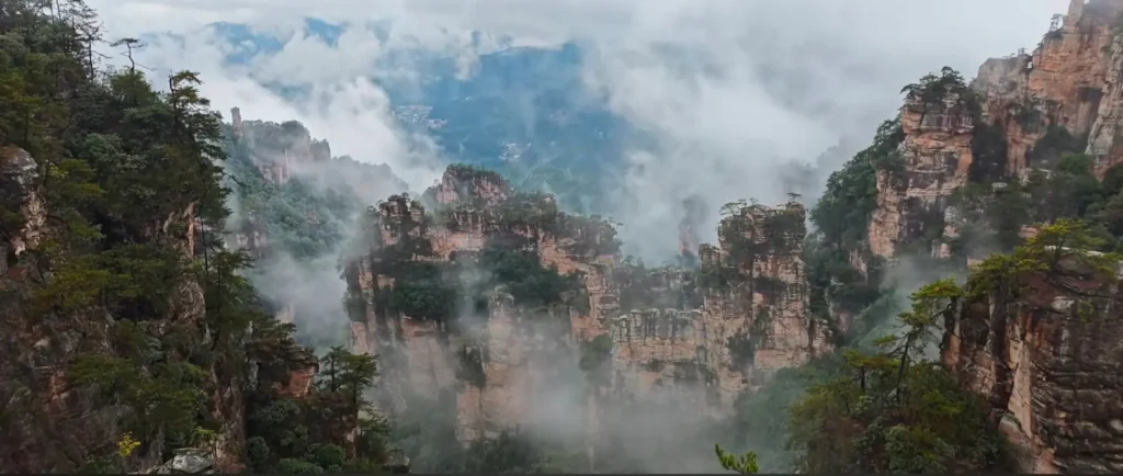 Panoramic sunny view of the Natural Great Wall sandstone peak walls as morning fog clears in Yangjiajie Scenic Area