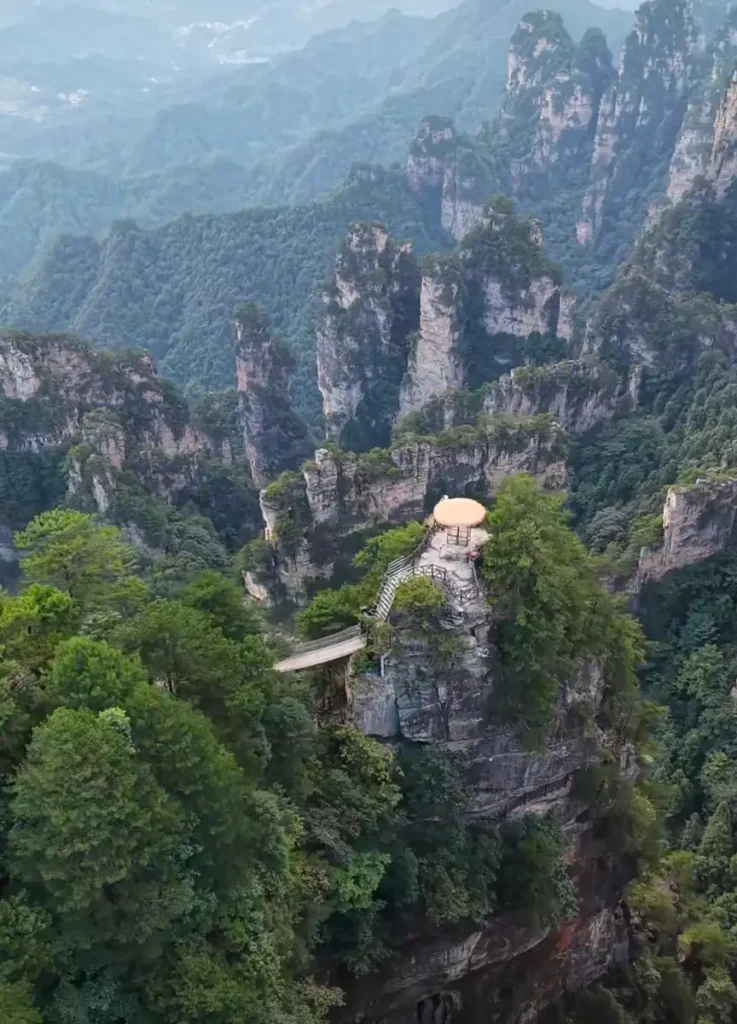 An aerial bird's-eye view of Tianbo Mansion rock platform surrounded by massive sandstone cliff walls in Yangjiajie