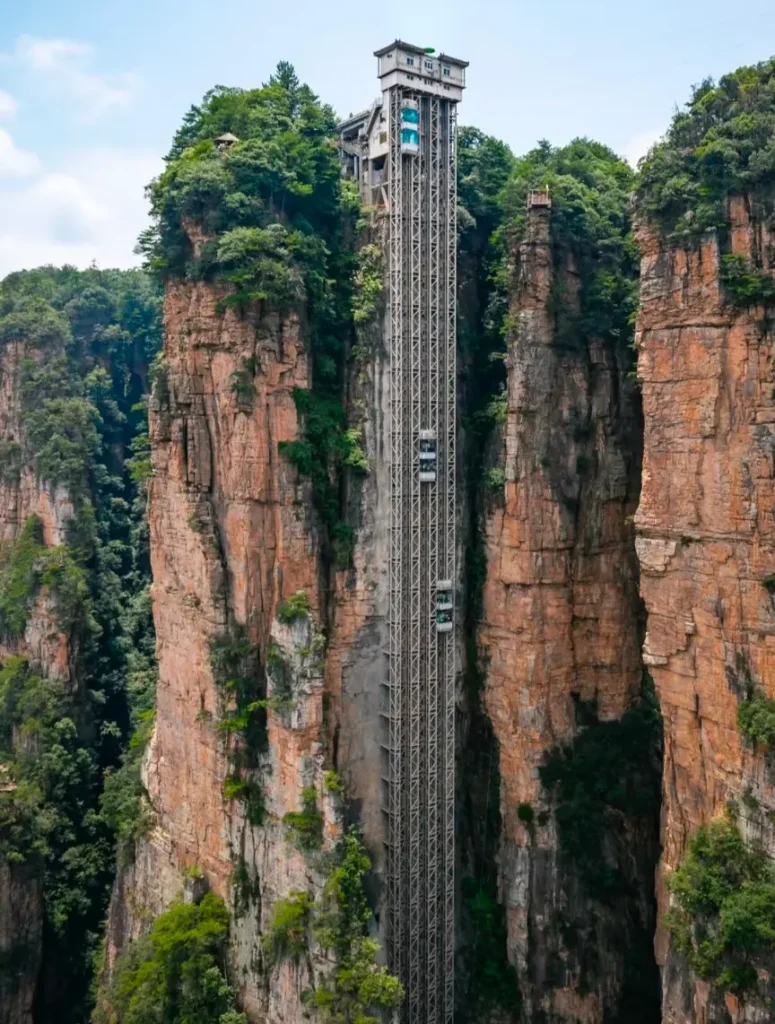 A distant view of the glass Bailong Elevator built directly into the side of a massive cliff in Zhangjiajie.
