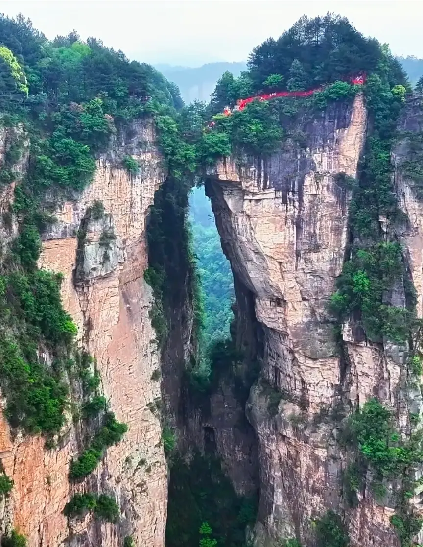 A distant view of the First Bridge Under Heaven, a natural stone bridge spanning across two massive cliffs in Yuanjiajie.