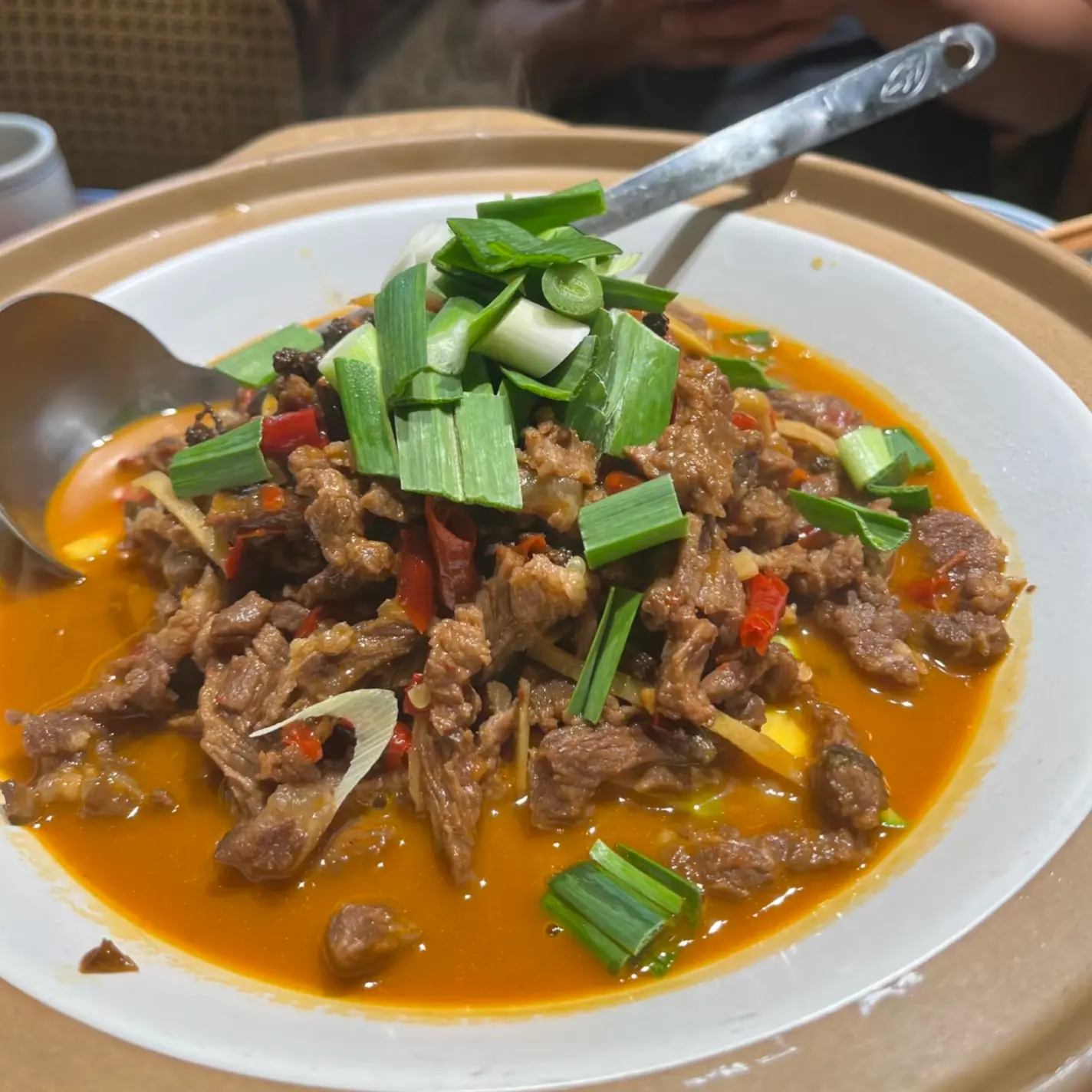 Close-up view of Dagupi, a signature Zhangjiajie spicy stir-fried beef dish served hot in a mini wok.