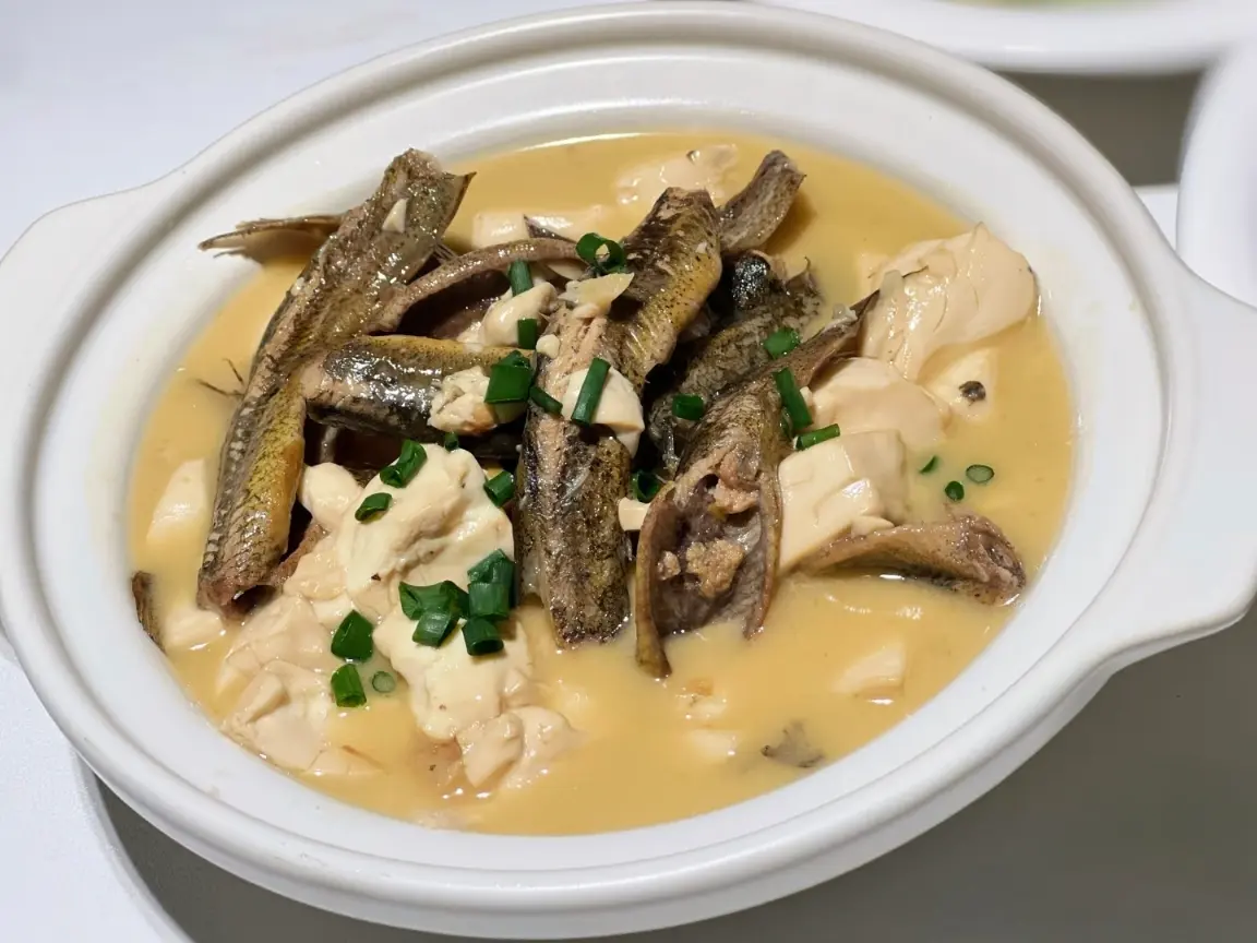 Close-up view of Loach in Tofu (泥鳅钻豆腐), a traditional Xiangxi specialty soup with soft tofu and braised loach.