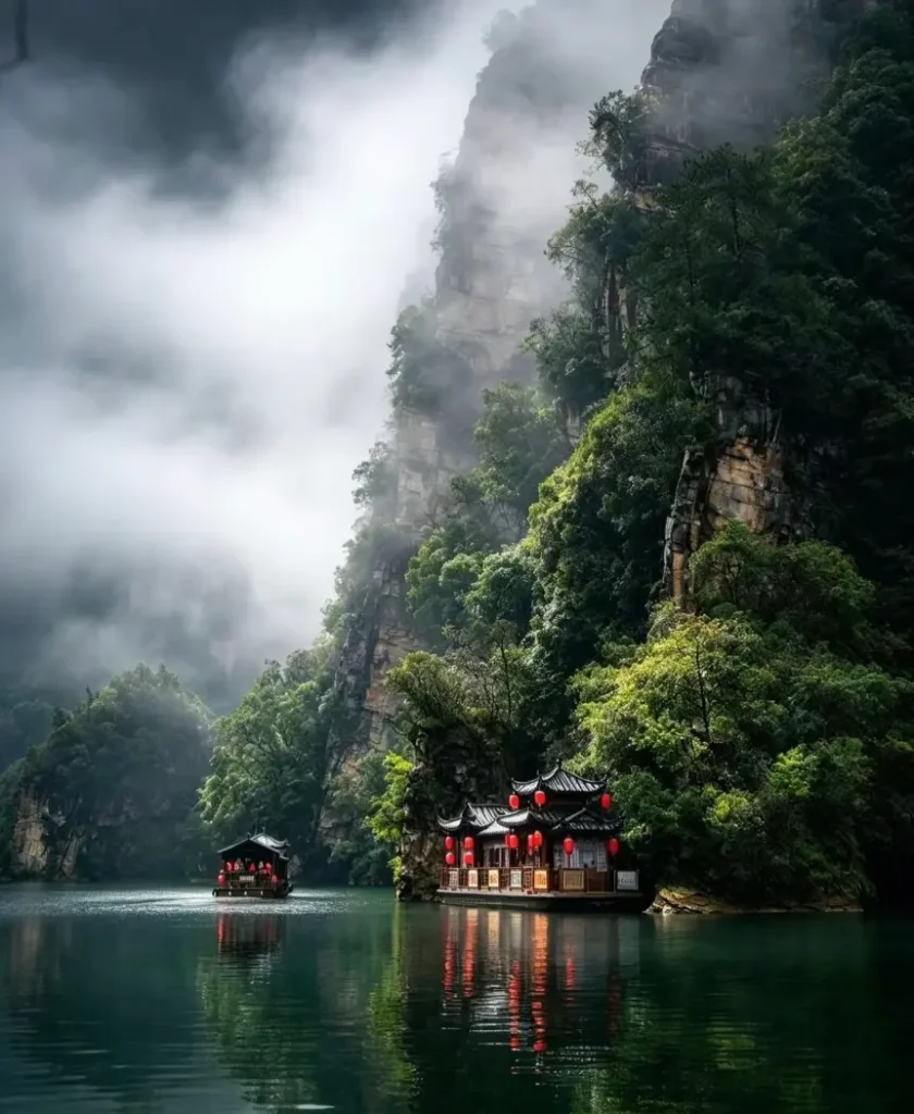 A wooden tour boat cruising across misty, emerald waters at Baofeng Lake in Suoxiyu